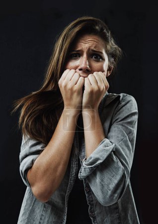 Photo for Portrait, horror and woman biting nails in studio on black background for reaction to fear or terror. Face, anxiety and mental health with scared young person in dark for stress, phobia or nightmare. - Royalty Free Image