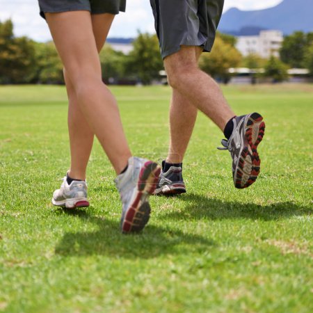 Téléchargez les photos : Les gens, les chaussures et courir sur l'herbe pour l'exercice ensemble en été pour la santé, le bien-être ou la formation. Personne, coureur et partenaire avec les pieds sur le terrain pour l'entraînement, la forme physique et la vitesse avec des baskets en plein air. - en image libre de droit