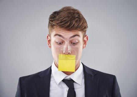 Photo for Business man, sticky note and mouth in studio for silence, reminder and thinking by white background. Person, employee or corporate workout with paper on lips for compliance, censorship and quiet. - Royalty Free Image