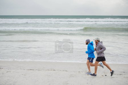 Photo for Ocean waves, men and running on beach, sand and fitness for wellness and gym wear on coast together. Male athletes, jog and training for seaside, health and outdoor for sport and exercise in workout. - Royalty Free Image