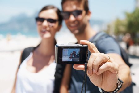 Téléchargez les photos : Couple, plage et appareil photo numérique pour selfie en vacances avec sourire, lunettes de soleil et extérieur pour la mémoire en été. Les gens, les hommes et les femmes avec la photographie par la mer pour le voyage, les vacances et l'écran en Italie. - en image libre de droit