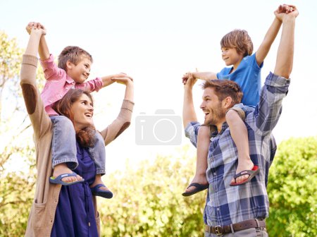 Foto de Sonríe, la naturaleza y los niños en los hombros de los padres en el parque al aire libre o el campo para jugar juntos. Feliz, vínculo y joven madre y padre llevando niños por diversión en el jardín en Canadá para el verano - Imagen libre de derechos