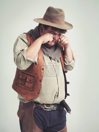 Photo for Cowboy person, crying and sad in studio, bandit and plus size man on white background. Dress up, fake and Halloween outfit or character, Texas criminals and vintage for retro theme in costume. - Royalty Free Image