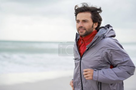 Photo for Beach, man or running for workout, training or wellness outdoor in nature to exercise for body health. Ocean, athlete or person jog for fitness, cardio or sport with energy at sea in winter on mockup. - Royalty Free Image