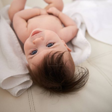 Photo for Baby boy, healthy and relaxing on blanket for comfort, care and infant development at home. Adorable child, growth and lying on bed rest in house, childhood and newborn with blue eyes and hair. - Royalty Free Image