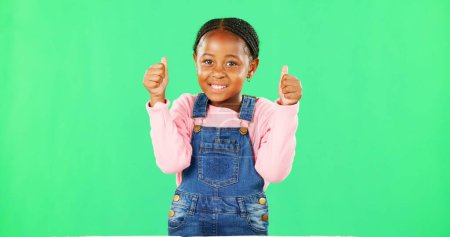 Photo for Child, thumbs up and portrait by green screen with smile for like, thanks or vote for agreement. Girl, African kid and happy with emoji, icon and sign language by chromakey with feedback for decision. - Royalty Free Image