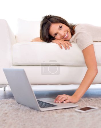 Photo for Woman, portrait and relax on sofa with laptop on floor for scroll, search or streaming in home living room. Girl, person and lying on couch with computer on carpet for movies, show or happy in house. - Royalty Free Image