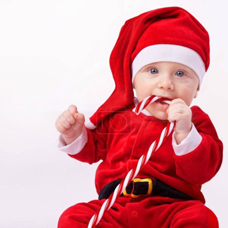 Photo for Baby, portrait and studio with santa costume for first Christmas holiday, candy cane and white background. Boy toddler, xmas and outfit for festive season or celebration, innocent and adorable in hat. - Royalty Free Image