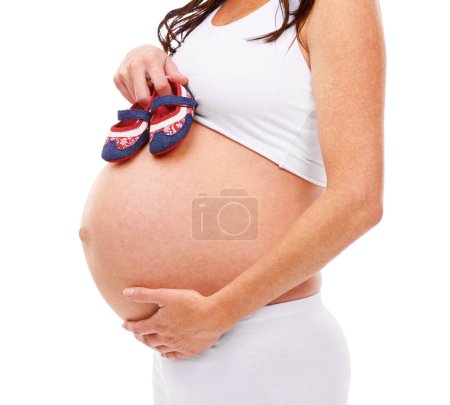 Photo for Pregnant, belly and baby shoes for hope, love and faith for future mother on white background. Pregnancy, stomach or cute footwear to ready for new, expectation of caring, healthy or maternity. - Royalty Free Image