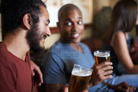 Foto de Amigos, cerveza y relajarse en el pub, sonreír y relajarse en el interior para la conversación y la vinculación por la noche para celebrar. Hombres, bar y felices por lo social, chicos y alcohol juntos y riendo por diversión - Imagen libre de derechos