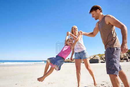 Photo for Happy family, swing and holding hands at a beach with love, support and care while bonding in nature. Freedom, travel and kid with parents at the ocean for morning games, fun or adventure at the sea. - Royalty Free Image