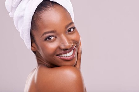 Photo for Hair towel, portrait and happy black woman in studio for skincare, wellness or body care on purple background. Beauty, cleaning or hands on face of African female model with cosmetic, shine or glow. - Royalty Free Image
