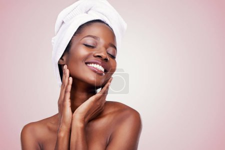 Photo for Hair, towel and happy black woman in studio for skincare, wellness or body care on pink background. Beauty, cleaning and hands on face of African female model with cosmetic, shine or glowing skin. - Royalty Free Image