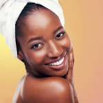 Portrait, smile and black woman with hair towel in studio for skincare, wellness or body care on orange background. Beauty, cleaning and face of African female model with cosmetic, shine or soft skin.