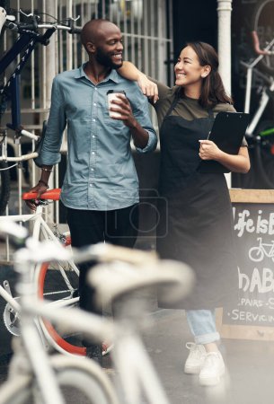 Foto de Cree que es la jefa. Foto completa de dos jóvenes propietarios de negocios de pie fuera de su tienda de bicicletas durante el día - Imagen libre de derechos