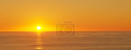 Foto de Océano, puesta de sol y sol en el horizonte para el paisaje y el destino turístico para las vacaciones de verano en la naturaleza. Cielo brillante, nubes y cielo dorado en la playa de la isla, paisaje marino y sol para el saludo del día. - Imagen libre de derechos