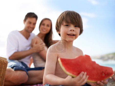 Photo for Portrait, parents and kid on beach with watermelon, picnic and tropical holiday in Australia. Mother, father and happy face of boy child relax at ocean with sunshine, eating fruit and smile in summer. - Royalty Free Image