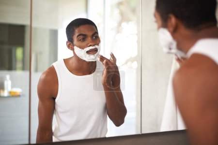 Téléchargez les photos : Homme noir, miroir et crème à raser sur le visage dans la salle de bain pour le toilettage, les soins de la peau ou la routine du matin. Réflexion, barbe et personne appliquer de la mousse pour le nettoyage, la santé et l'épilation pour l'hygiène à la maison. - en image libre de droit