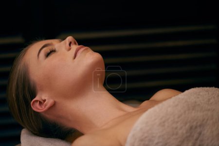 Photo for Woman, lying and relax in spa for wellness or peace, massage therapy or skincare and calm to free tension. Female person, resort and luxury for stress relief or rest for wellbeing with aromatherapy - Royalty Free Image