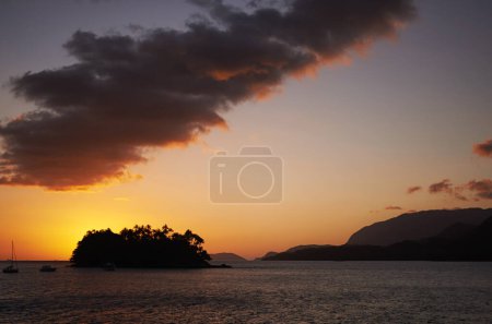 Photo for Tropical, island and ocean with sunset on horizon, travel and relax morning in nature in summer. Holiday destination, calm or boats on sea for vacation, night or view of mountain in beach landscape. - Royalty Free Image