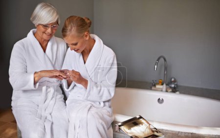 Photo for Mother, spa and manicure with daughter, bath and senior woman for bonding and relaxation. Parent, robe and nail polish with cosmetics, guidance and support with beauty treatment or pamper and glasses. - Royalty Free Image