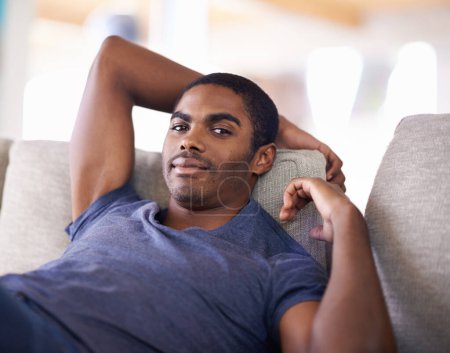 Photo for Man, portrait and smile on sofa with relax in living room of home with comfort, confidence or weekend. Student, african person and happiness with face on couch in lounge for rest, day off or wellness. - Royalty Free Image