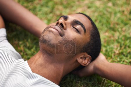 Photo for Face, relax and black man on grass in garden of summer home for peace, wellness or mindfulness. Nature, field and sunshine with happy young person lying on green ground from above for break or rest. - Royalty Free Image