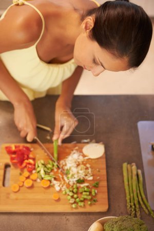 Photo for Cooking, food and health with chef in kitchen of home to prepare meal for diet or nutrition from above. Woman, nutritionist or vegan and person cutting green vegetables with knife in apartment. - Royalty Free Image
