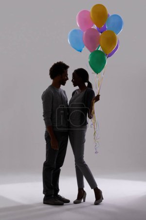 Photo for Couple, silhouette and party with balloons for celebration, event or romance on a gray studio background. Man and woman holding colorful objects of helium for art, date or anniversary on mockup space. - Royalty Free Image