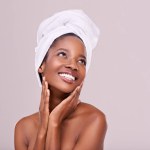 Black woman, skin care and natural for beauty, studio and wellness in fresh look with smile and face touch. African female person, soft cosmetic and aloe vera for anti age, nude and confidence.