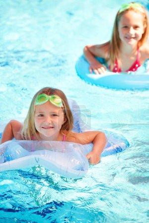 Photo for Swimming, inflatables and portrait of kids in pool, playing and summer at resort on vacation. Holiday, games and friends relax in water with toys for fun, activity or children with safety gear. - Royalty Free Image