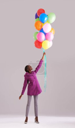 Téléchargez les photos : Ballon, couleur et femme noire en studio pour anniversaire, célébration et cadeau. Heureux, excité et wow avec le sourire isolé de personne avec gonflable pour la partie, le cadeau et la surprise sur fond gris. - en image libre de droit