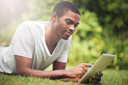 Photo for Relax, happy and tablet with black man on grass of garden for research or information in summer. Technology, internet and young person reading online ebook on green field outdoor in backyard. - Royalty Free Image