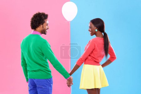 Photo for Happy, couple and holding hands with balloon in studio for gender reveal on pink and blue background with fashion. Back, woman and man excited together with support in pregnancy, news or announcement. - Royalty Free Image