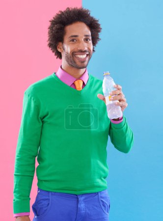 Photo for Fashion, black man and smile in studio with water in bottle on color block background for health, hydration and wellbeing. Portrait, male person and happy with trendy outfit for style and formal - Royalty Free Image