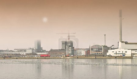 Photo for Harbor, industrial buildings and town in outdoors, treatment plant and development by factory. Production, warehouse and power station or refinery in Aarhaus, Denmark and river or lake outside. - Royalty Free Image