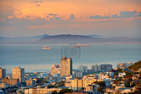 Photo for City, building and ocean sunset with development infrastructure for summer holiday, explore or downtown. Water, urban and sea or mountain in South Africa or calm nature or evening, vacation or trip. - Royalty Free Image