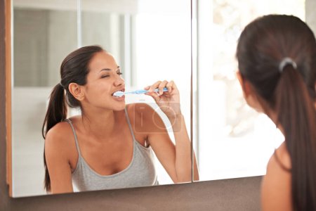 Foto de Espejo, baño y mujer con cepillo de dientes para el bienestar, higiene bucal y cuidado dental en el hogar. Pasta dental, cuidado de la salud y reflexión de la persona cepillándose los dientes para blanquear, limpiar y acicalar. - Imagen libre de derechos