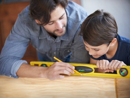 Photo for Father, kid and wood work at home for carpenter, bonding and building with safety gear. Dad, son and builder for renovating, measuring and teaching moment for development of house with learning. - Royalty Free Image