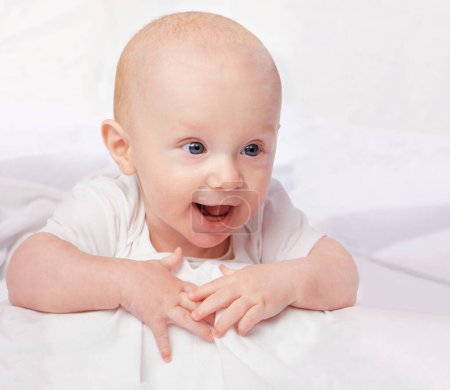 Photo for Baby, excited and smile with laying on bed for curiosity, child development and relax on bed at house. Adorable, kid and cute infant in home for playful, laugh and fun with happiness in nursery. - Royalty Free Image
