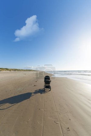 Photo for Stroller, sand and blue sky with cloud by beach for travel, vacation or holiday in summer. Baby pram, nature and ocean by seashore for tropical weekend trip on outdoor island destination in Cape town. - Royalty Free Image