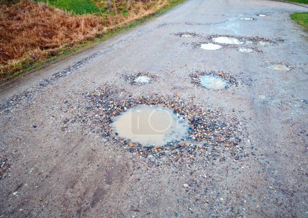 Photo for Water, gravel and road in countryside with pothole with maintenance, infrastructure and farm transport in winter. Dirt, path and rain puddle in hole on rural street with damage, ground and nature - Royalty Free Image