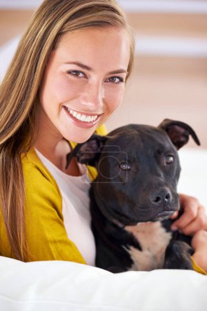 Foto de Mujer, perro y feliz en sala de estar en retrato, sonrisa para el amor de mascotas y vinculación en casa con canino doméstico. Relajarse, positivo y confiar en el fomento o adopción, pitbull cachorro y cuidado de animales en el sofá. - Imagen libre de derechos