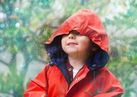 Photo for Child, rain and raincoat in style for fashion, jacket or cold weather in winter. Little boy, male toddler and kid in drizzle by tree, bokeh or environment with windbreaker for chilly season in London. - Royalty Free Image