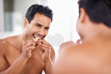 Foto de Salud dental, espejo y hombre en baño para limpieza de dientes, autocuidado y rutina matutina. Higiene bucal, diente y cara de hombre en casa para el bienestar, hilo dental y encías con reflexión - Imagen libre de derechos