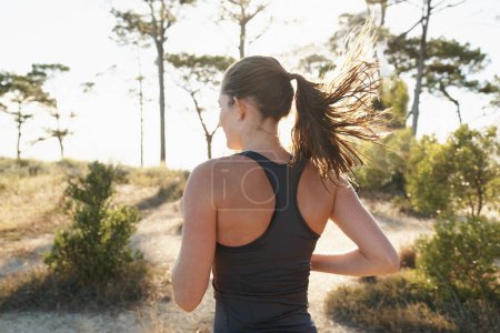 Téléchargez les photos : Fitness, course et femme sur le chemin de la forêt pour la santé, le bien-être et le fort développement du corps. Entraînement, exercice et fille coureuse sur route dans la nature pour l'entraînement au marathon, la performance et le défi - en image libre de droit
