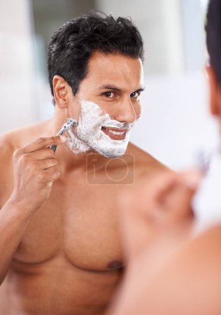 Téléchargez les photos : Homme, épilation et crème à raser sur le visage dans le miroir de salle de bain pour lame de rasoir, toilettage et beauté. Soins de la peau, bien-être et personne masculine pour l'auto-soin, la routine matinale ou l'hygiène avec réflexion - en image libre de droit