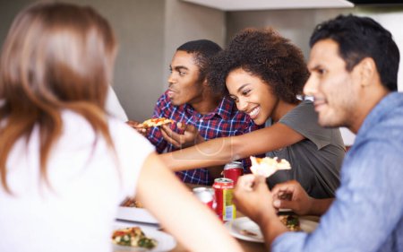 Téléchargez les photos : Amis, groupe et manger de la pizza à la maison avec rire, soda et rassemblement social pour coller dans la salle à manger. Hommes, femmes et restauration rapide avec sourire, drôle et diversité à table dans le salon de la maison. - en image libre de droit