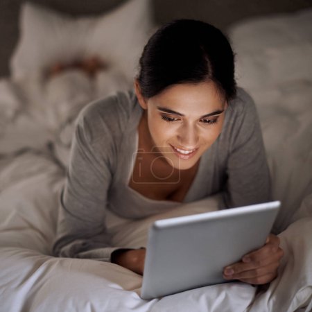 Photo for Night, bedroom and woman with smile for tablet on social media, chatting and texting on site of app. Bed, female person and girl with technology for reading ebook to relax and online with internet. - Royalty Free Image