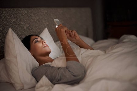 Woman, scrolling and phone for social media, bed and relaxation under blankets in pajamas to sleep. Female person, browse and tech for peace, night and online for conversation, chat and memes.